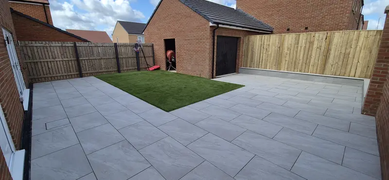 Large grey patio and lawn at a new-build home
